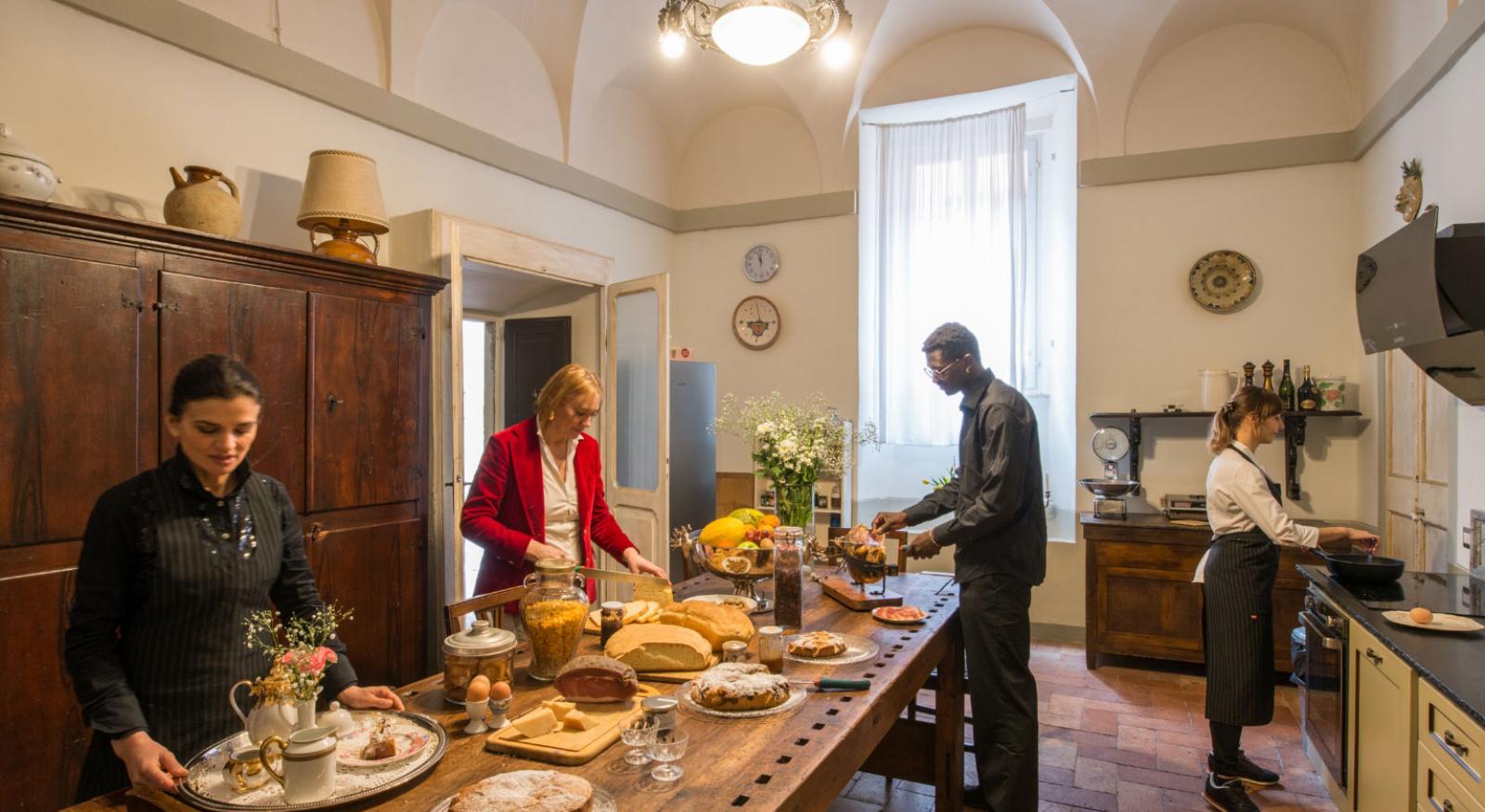 Persone cucinano e preparano cibo in una cucina con arredamento rustico.