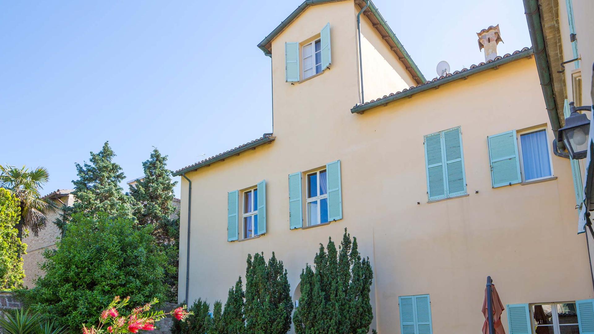 Casa con persiane azzurre e giardino verde.