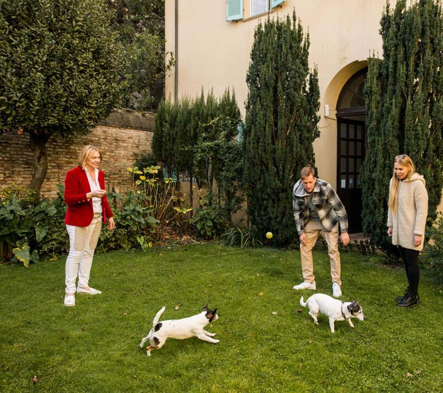 Famiglia gioca con due cani nel giardino di una casa.