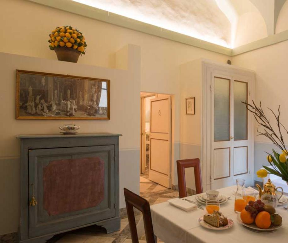 Sala da pranzo luminosa con fiori freschi, frutta e arredi eleganti.