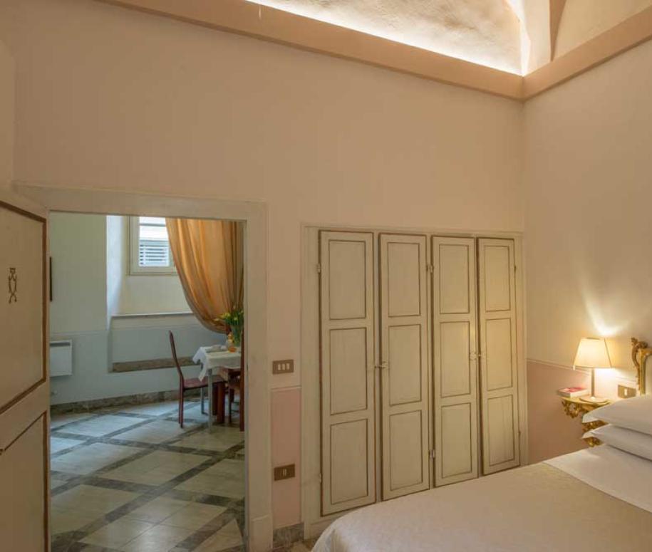 Camera da letto elegante con dettagli classici e accesso a una sala da pranzo.