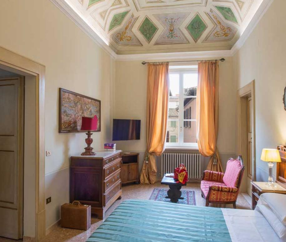 Camera d'hotel elegante con soffitto decorato e arredi classici.
