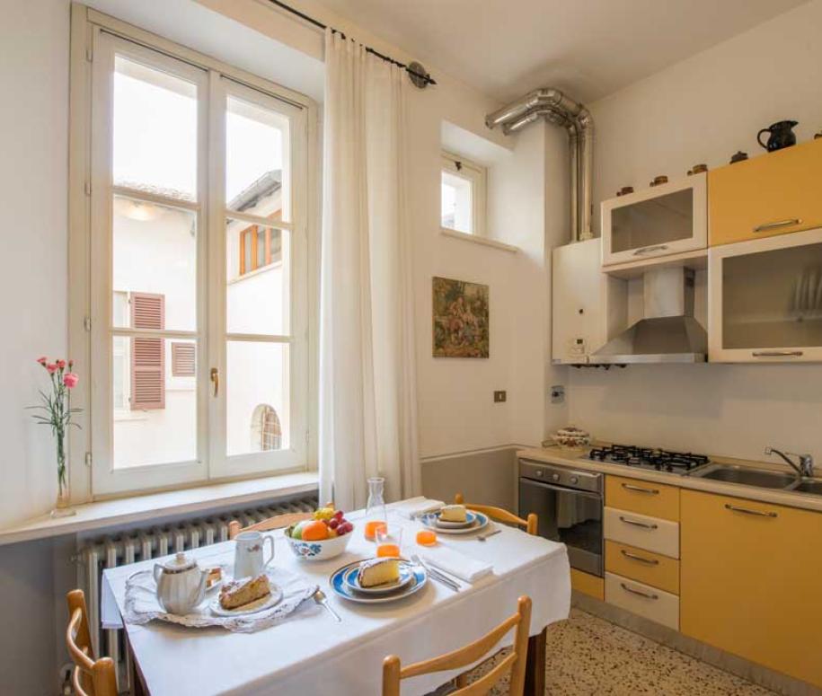 Cucina luminosa con mobili gialli e tavolo apparecchiato per la colazione.