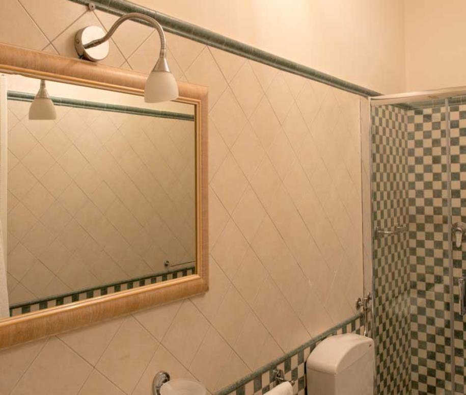 Bagno con doccia a mosaico, specchio grande e illuminazione moderna.