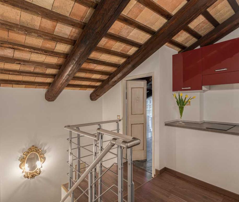Piccola cucina con soffitto in legno e armadi rossi.