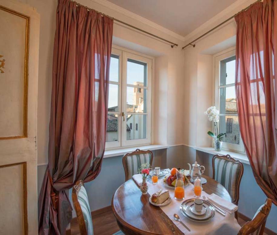 Accogliente angolo colazione con tavolo apparecchiato, tende eleganti e vista sulla città.