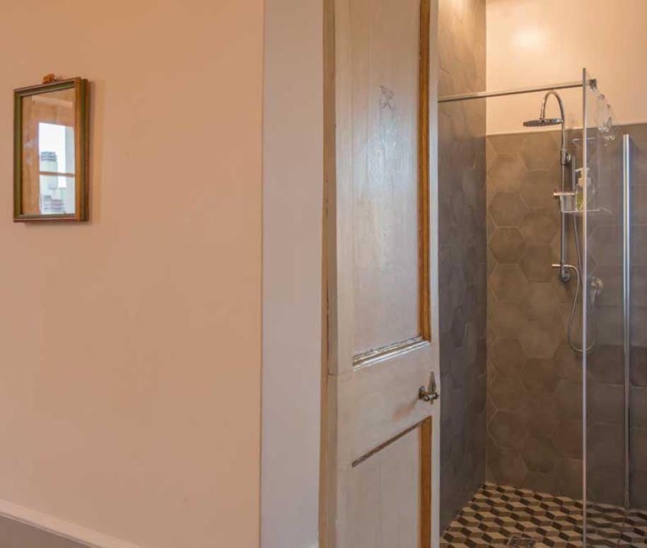 Bagno con doccia moderna, piastrelle esagonali e finestra con tenda.