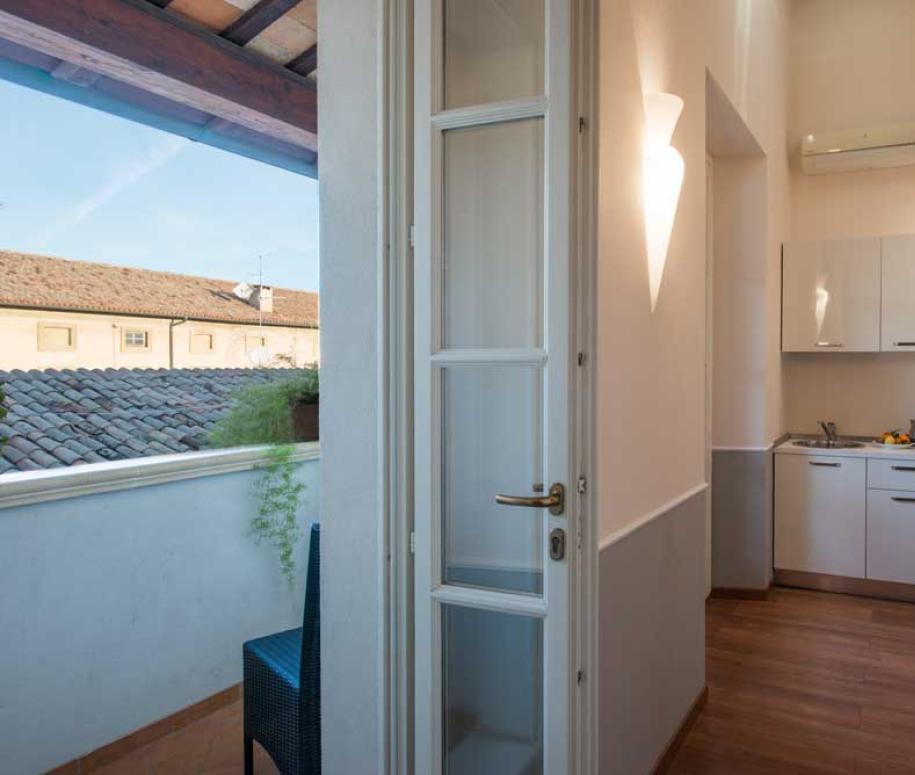 Cucina moderna con balcone, pavimento in legno e vista sui tetti.