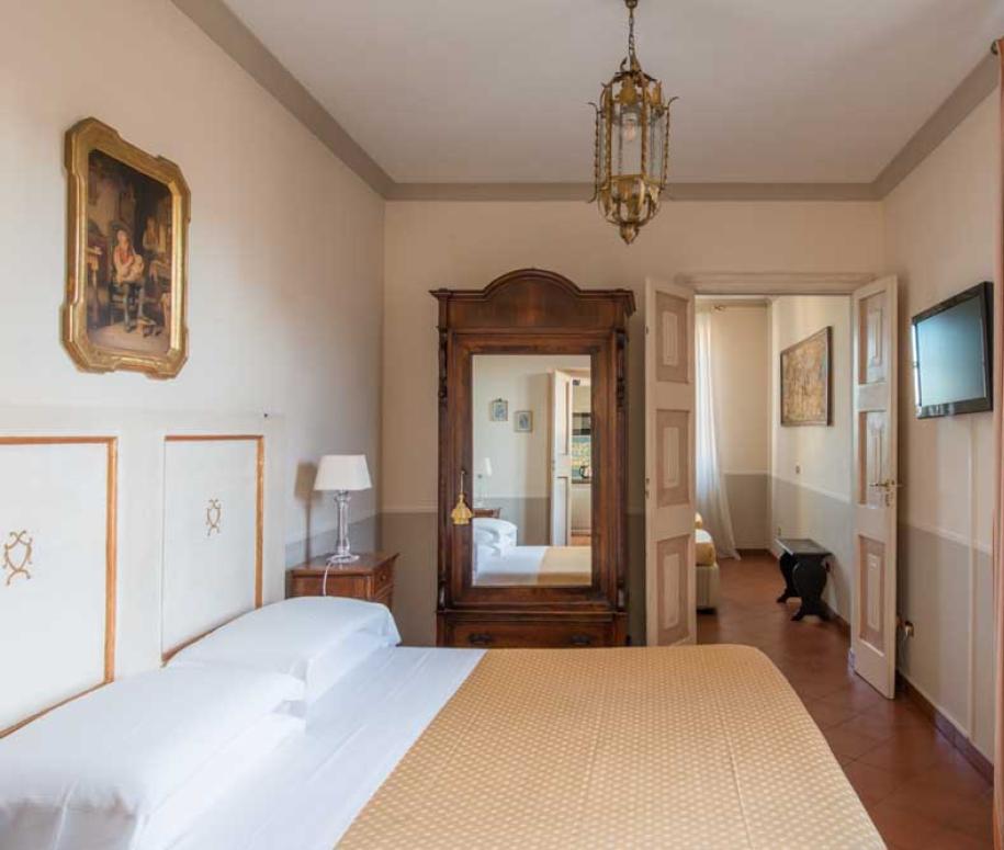 Camera da letto accogliente con letto matrimoniale, armadio antico e TV a schermo piatto.