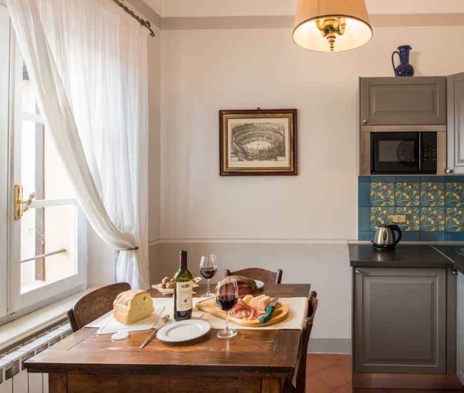 Cucina accogliente con tavolo apparecchiato, vino e cibo, decorazioni vivaci.