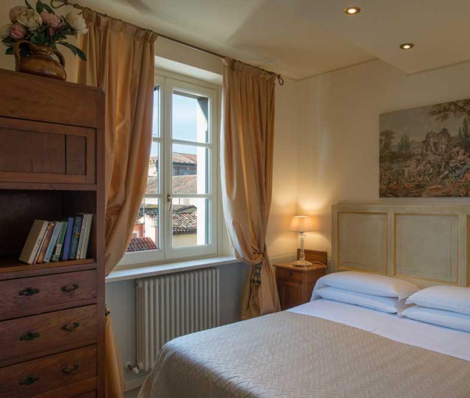 Accogliente camera da letto con finestra, tendaggi dorati e arredo classico.