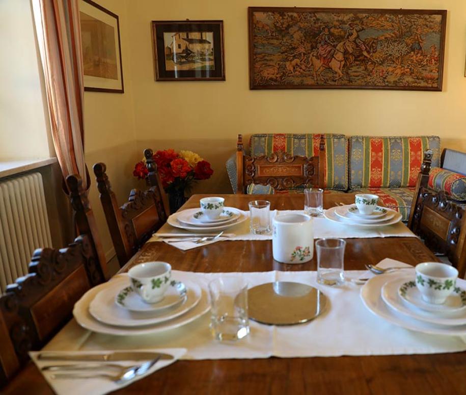 Sala da pranzo accogliente con tavola apparecchiata e divani colorati.