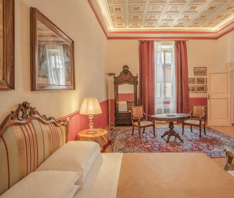 Camera elegante con arredi classici, soffitto decorato e tendaggi raffinati.
